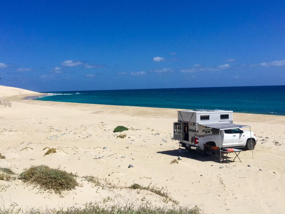 pop up truck parked on the beach next to the ocean