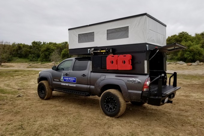 A lightweight pop-up camper attached to a truck.