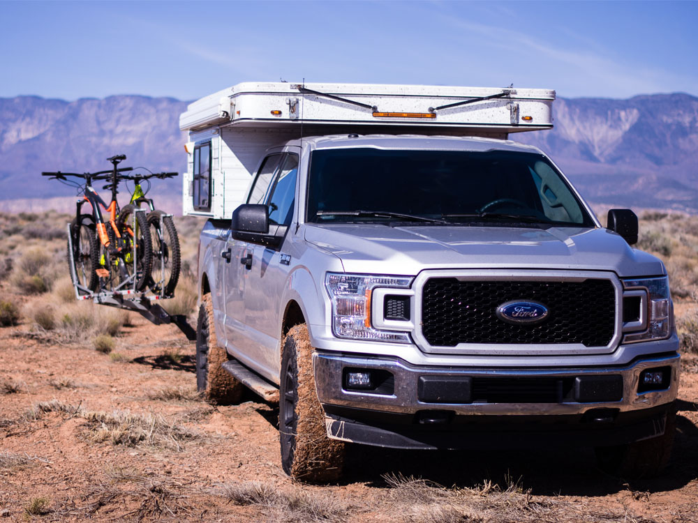 Truck with a pop up camper and bicycles mounted in the back